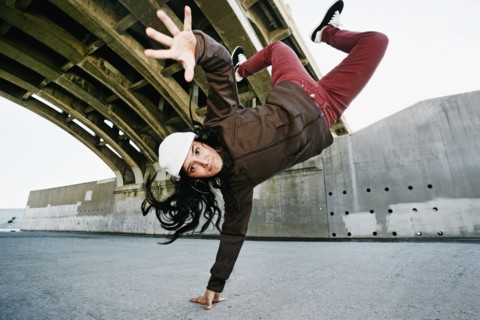 Hispanic woman break dancing under overpass