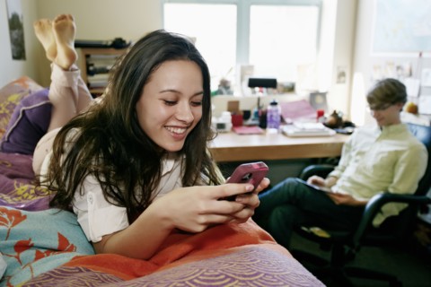 Mixed race college student using cell phone in dorm