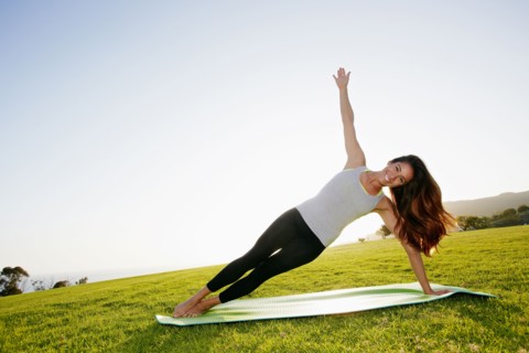 Mixed race woman practicing yoga in park