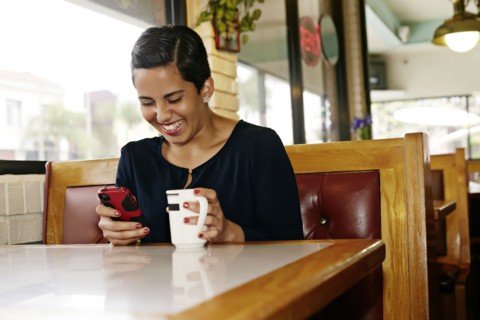 Hispanic businesswoman using cell phone in restaurant