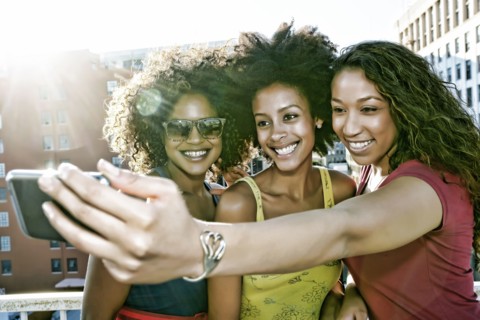 Mixed race women taking self-portrait on urban rooftop