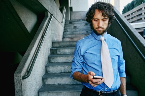 Caucasian businessman using cell phone on urban stairs