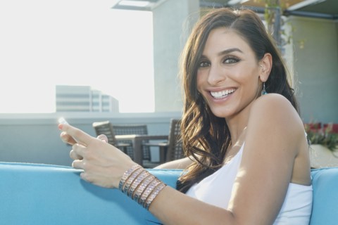 Middle Eastern woman using cell phone on sofa