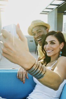 Couple taking self-portrait on sofa on balcony