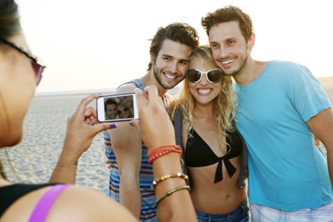 Friends taking pictures together on beach