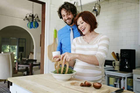 Pregnant Caucasian couple cooking in kitchen
