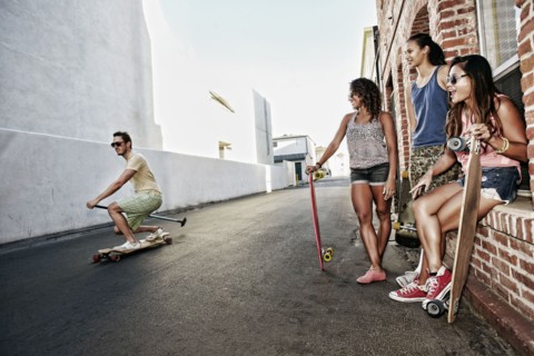 Friends riding longboards on city street