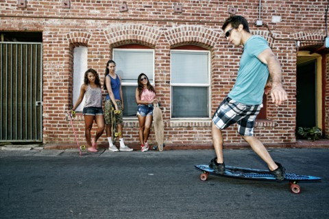 Friends riding longboards on city street
