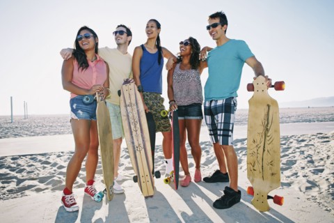 Friends holding longboards on beach