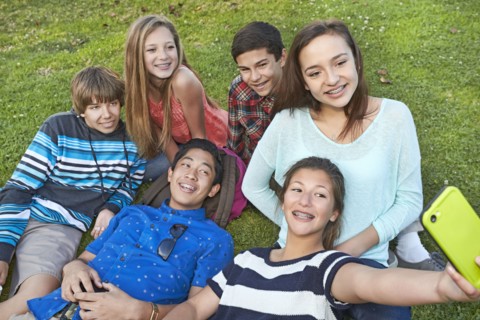 Teenagers taking picture together in grass