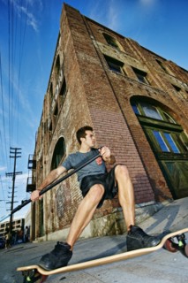 Caucasian man riding skateboard with land paddle