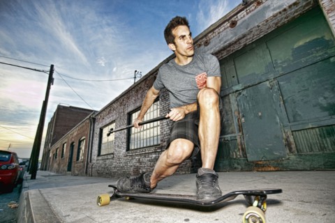 Caucasian man riding skateboard with land paddle