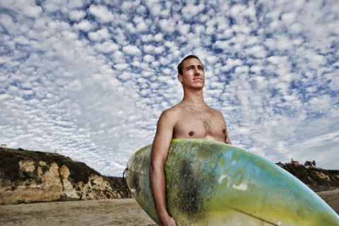 Caucasian man carrying surfboard on beach