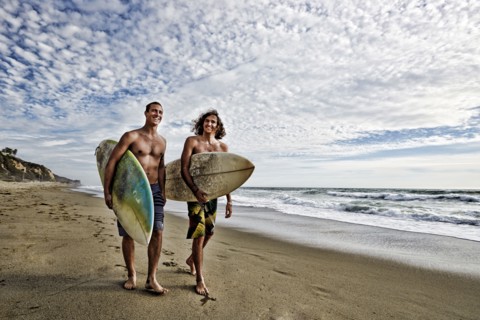 Caucasian men carrying surfboards on beach