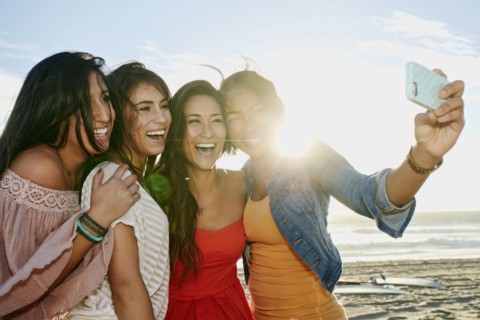Women taking pictures together on beach
