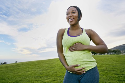 Pregnant woman laughing in park