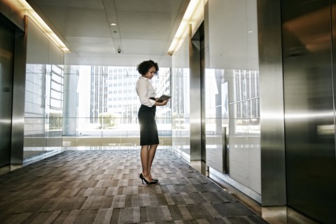 Mixed race businesswoman using tablet computer in lobby
