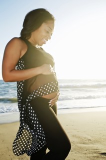 Pregnant woman holding her belly on beach