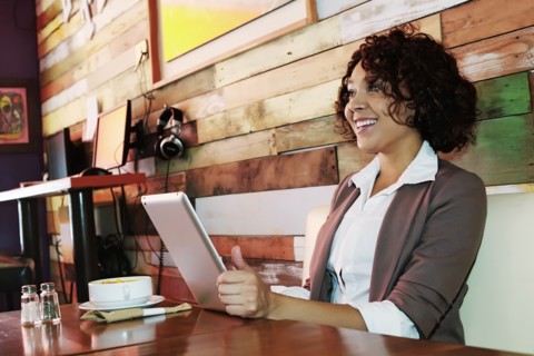 Mixed race woman using tablet computer in cafe