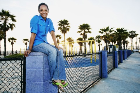 Older Black woman relaxing by park on beach