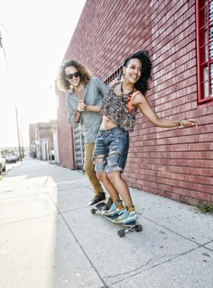 Couple riding skateboard on city street