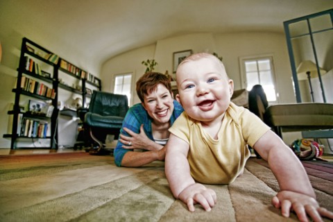 Caucasian mother and baby playing on living room floor