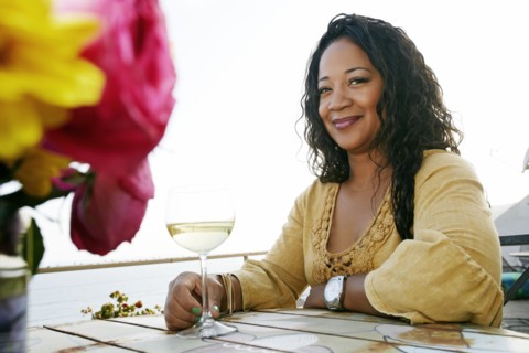 Mixed race woman drinking wine at waterfront