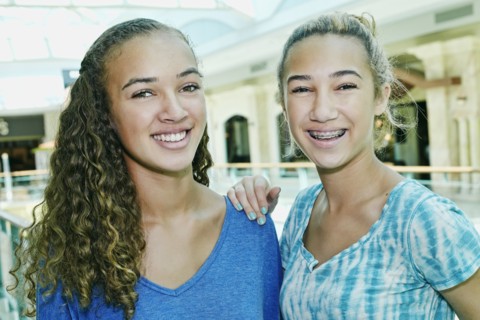 Mixed race teenage girls smiling at shopping mall
