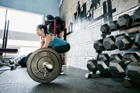 Mixed race woman lifting weights in gym
