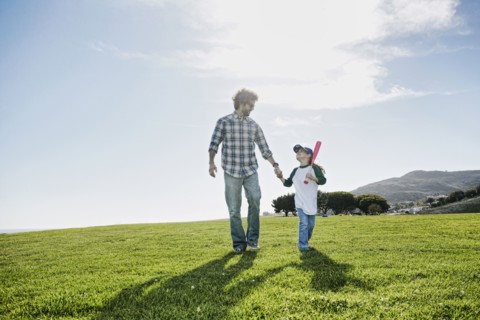 Father and daughter walking in grassy field