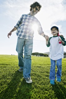 Father and daughter walking in grassy field