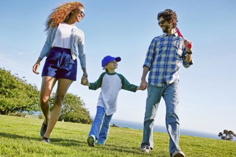 Parents and daughter walking in grassy field
