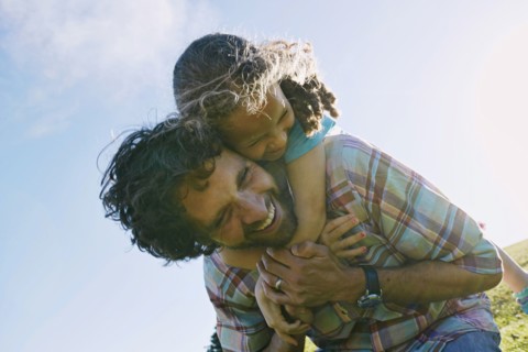 Low angle view of father carrying daughter piggyback outdoors