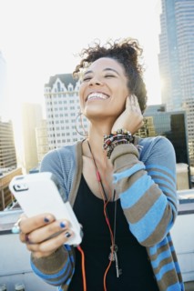 Mixed race woman listening to earbuds on urban rooftop