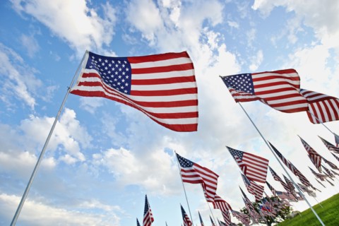Low angle view of American flags under blue sky