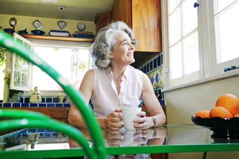 Caucasian woman drinking cup of coffee in kitchen