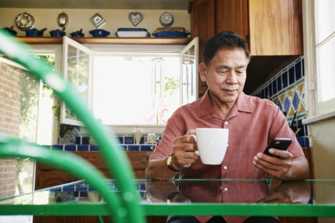 Filipino man using cell phone in kitchen