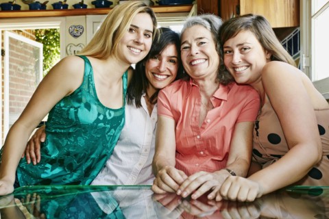 Caucasian mother and daughters hugging in kitchen