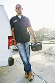 Mixed race plumber holding tools van