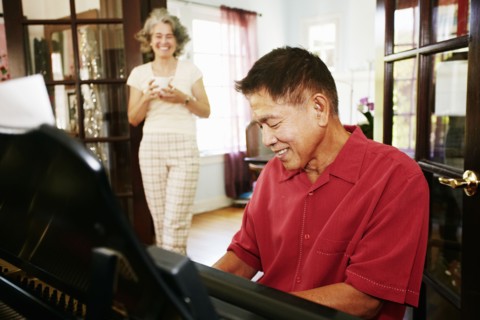 Woman watching husband playing piano in living room
