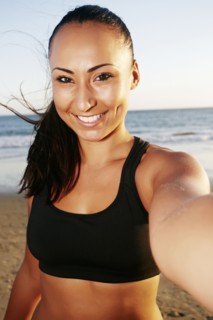 Mixed race woman taking cell phone selfie on beach