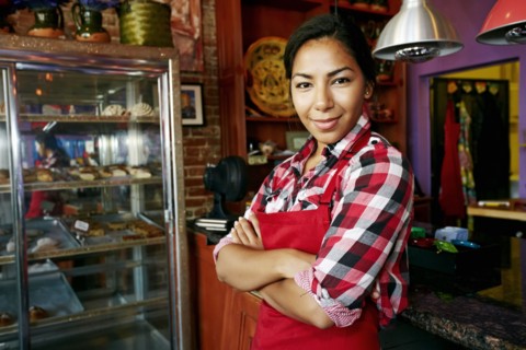 Hispanic waitress smiling in bakery