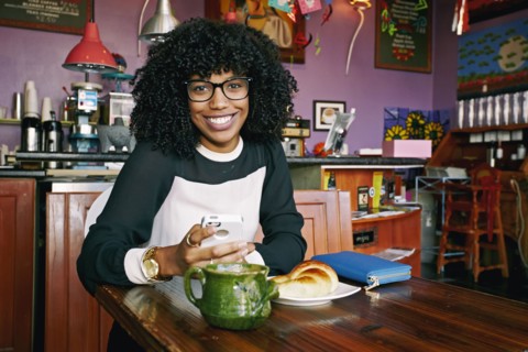 Mixed race woman using cell phone in cafe