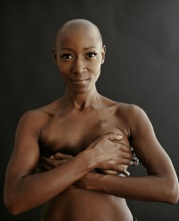 Nude African American cancer survivor covering her breasts