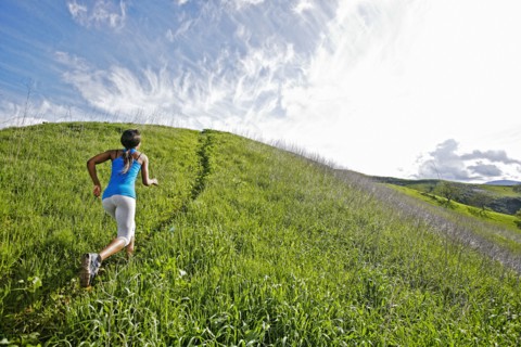 Black athlete running on rural hillside