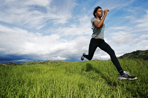 Black athlete running in rural field