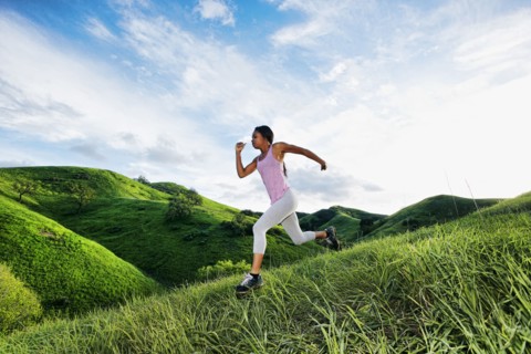 Black athlete running on rural hillside