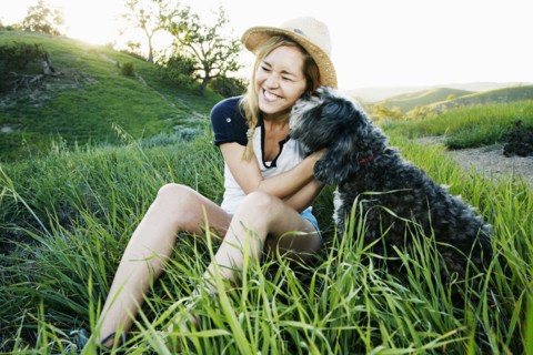 Caucasian woman petting dog in field