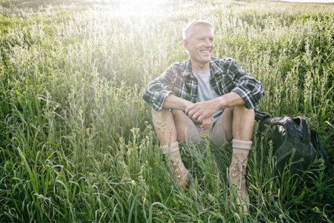 Older Caucasian man sitting on grassy hillside