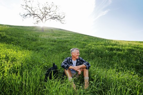 Older Caucasian man sitting on grassy hillside